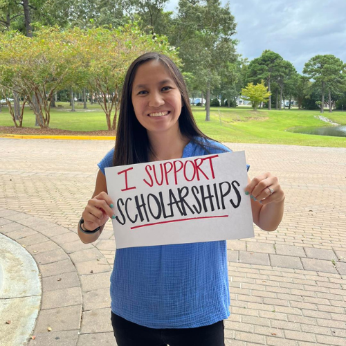 employee holding sign that says I support scholarships