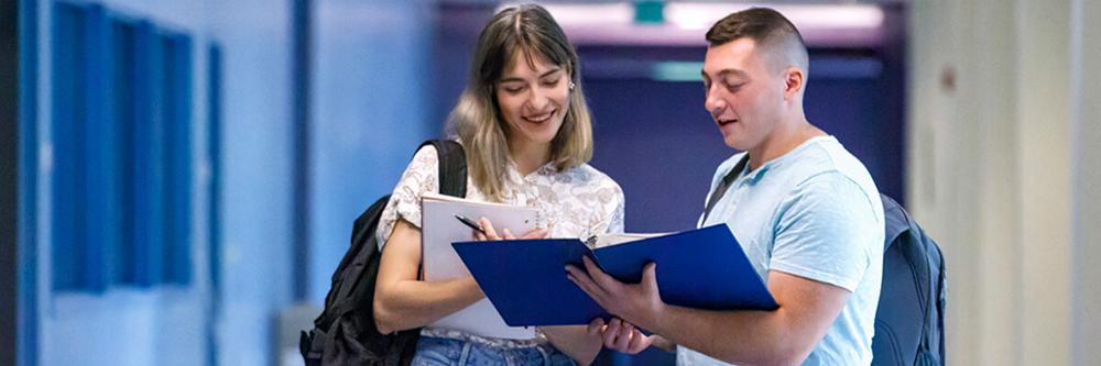 Two students looking over paperwork together.