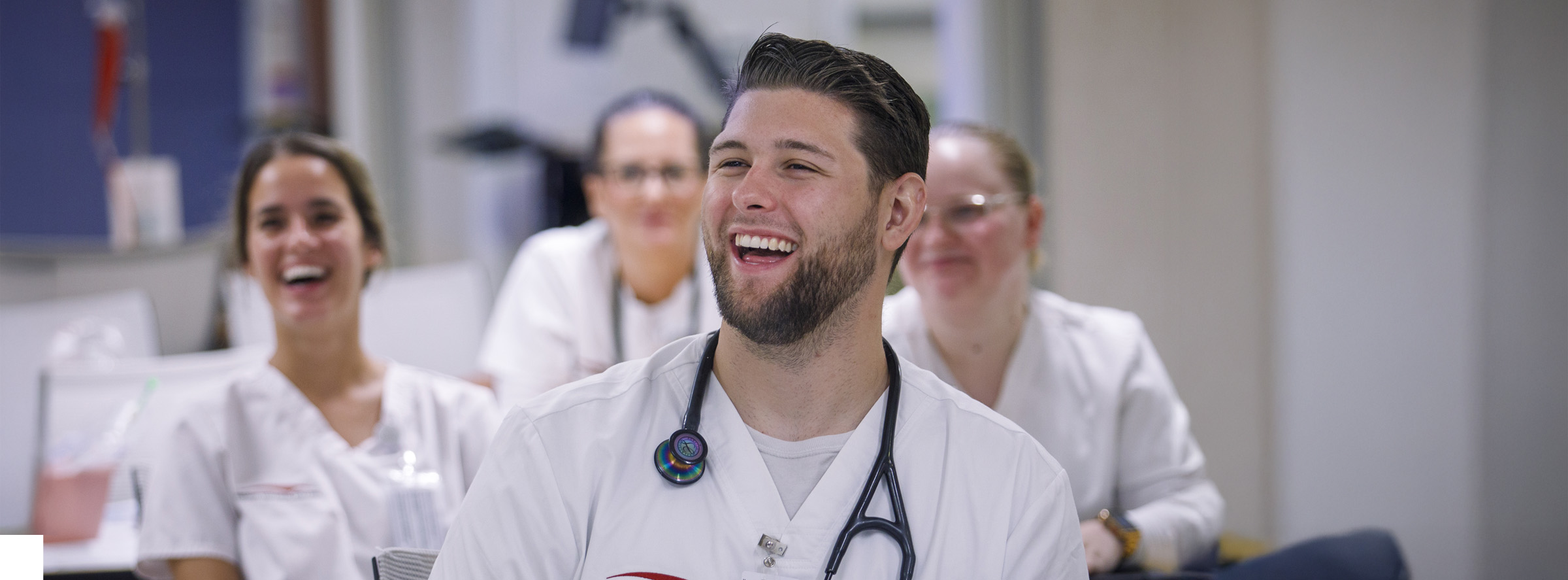 Nursing students in clinical scrubs laughing together in a healthcare setting