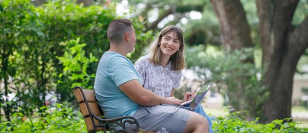 Students smiling at each other in a park.