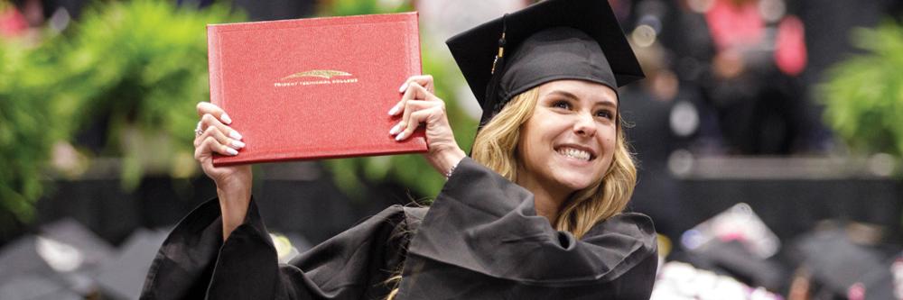 A new TTC graduate holds up her diploma.