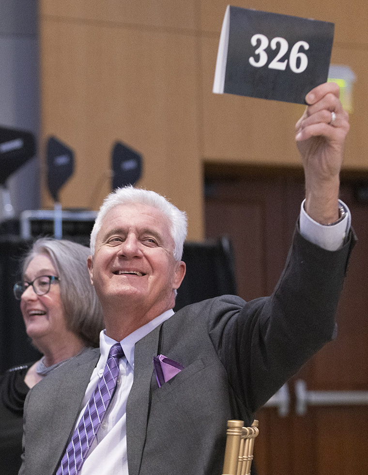 A guest raising a bid paddle during the auction at the 2026 event.