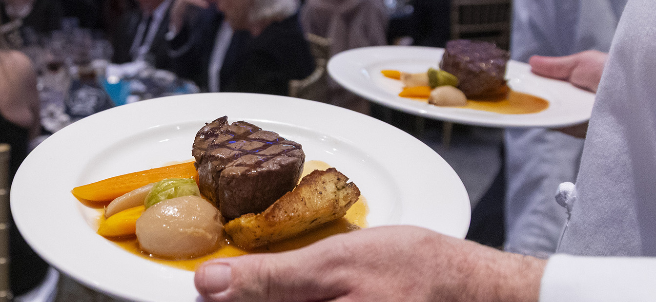 A plated main course being carried to a table.