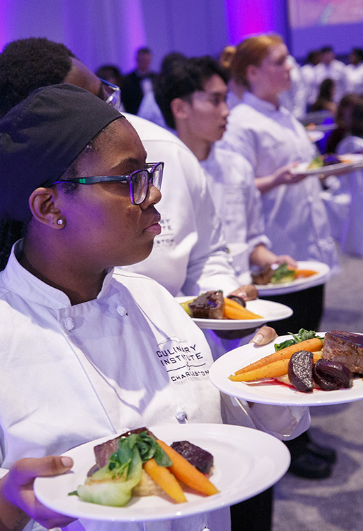 Culinary Institute of Charleston students carrying plated courses into the dining room.