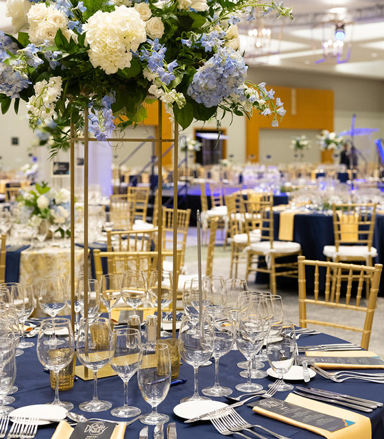 An event table set for dinner with a large flower center piece.