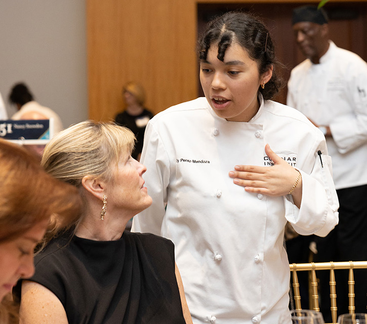 A student chef speaking with a guest.