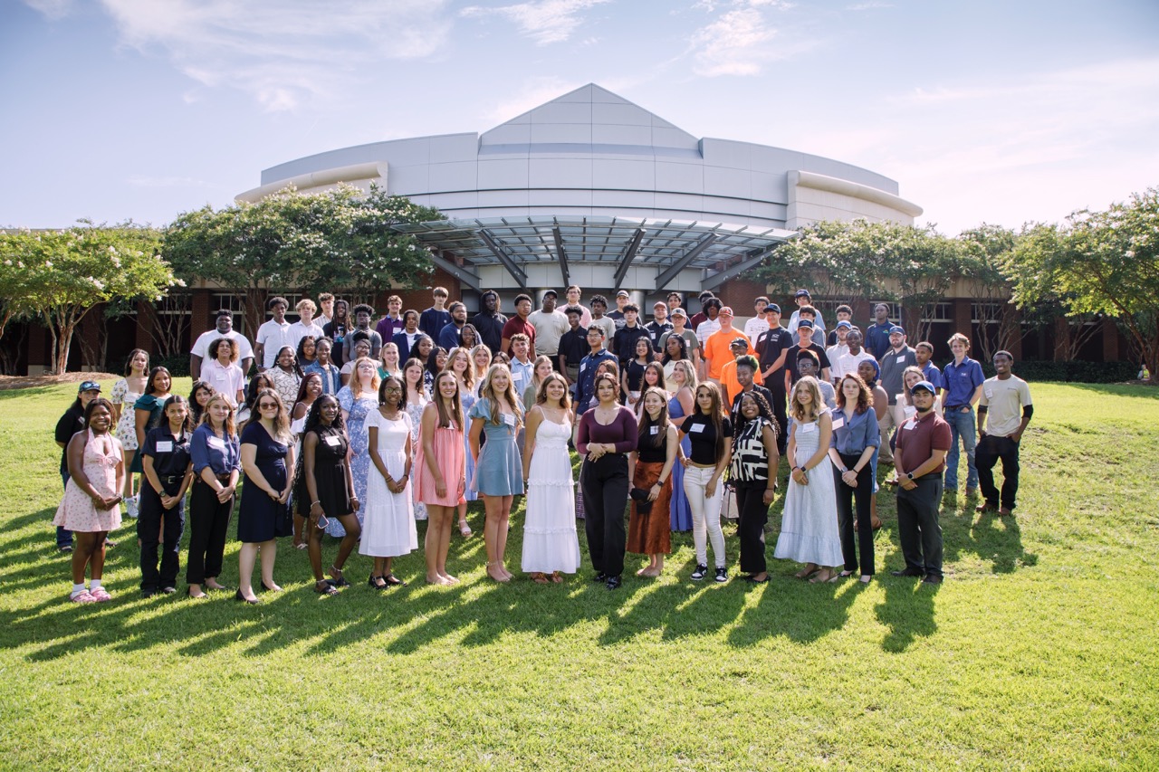 Youth apprentices pose for a group photo in the school courtyard.